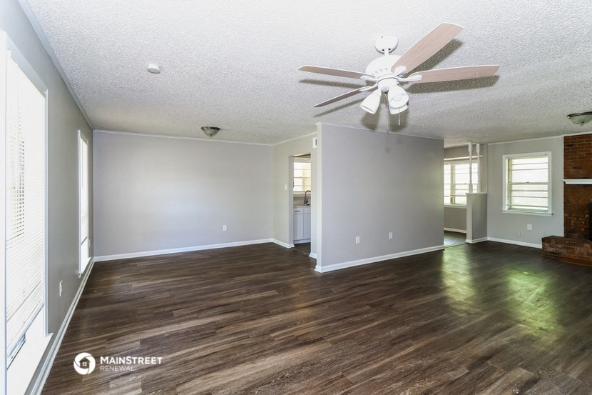 the living room and dining room of an empty house with a ceiling fan