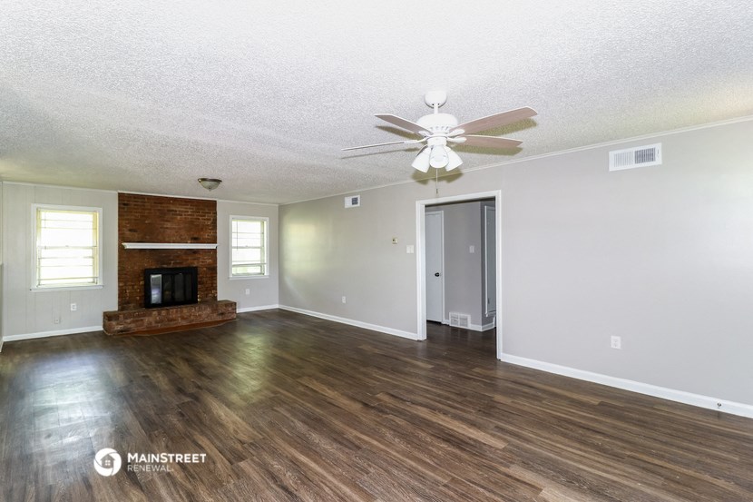 an empty living room with a fireplace and a ceiling fan