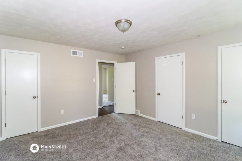 a empty living room with three doors and a carpeted floor