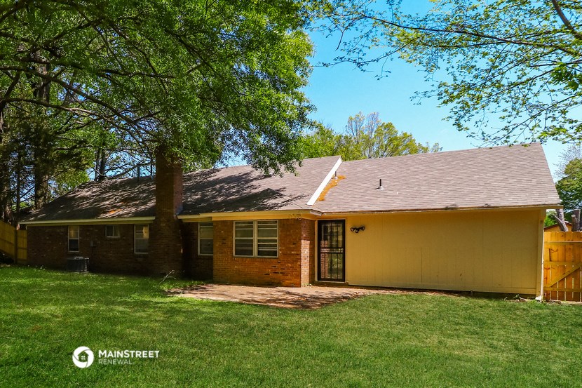 front view of a yellow house with a yard and trees