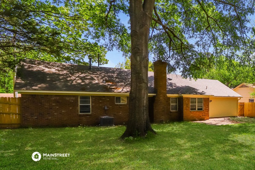 a brick house with a large tree in front of it