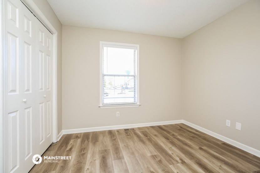 an empty room with wooden floors and a window