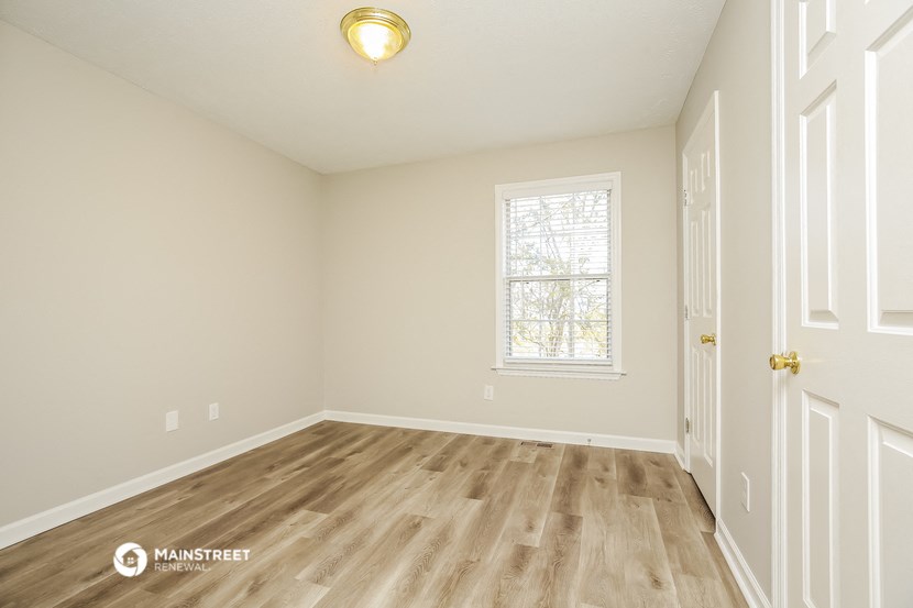 the spacious living room with hardwood flooring and a window