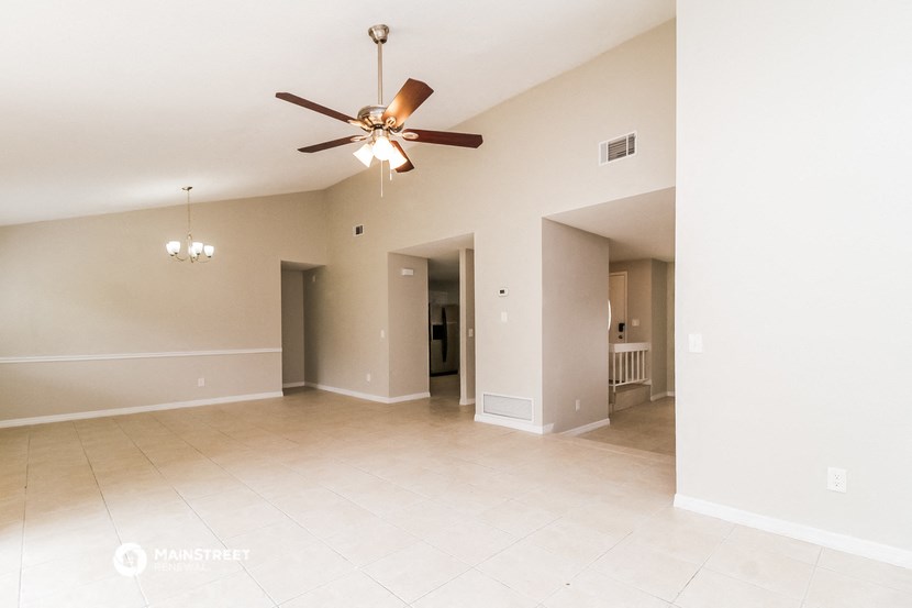 the spacious living room with ceiling fan and tiled floors