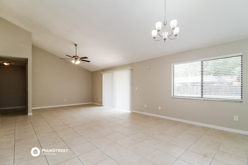 an empty living room with a ceiling fan and a large window