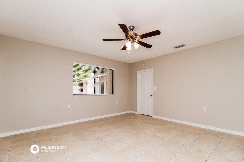 the spacious living room with ceiling fan and tile flooring