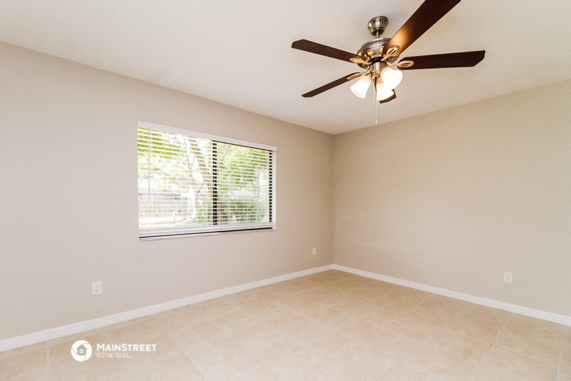 the spacious living room has a large window and a ceiling fan