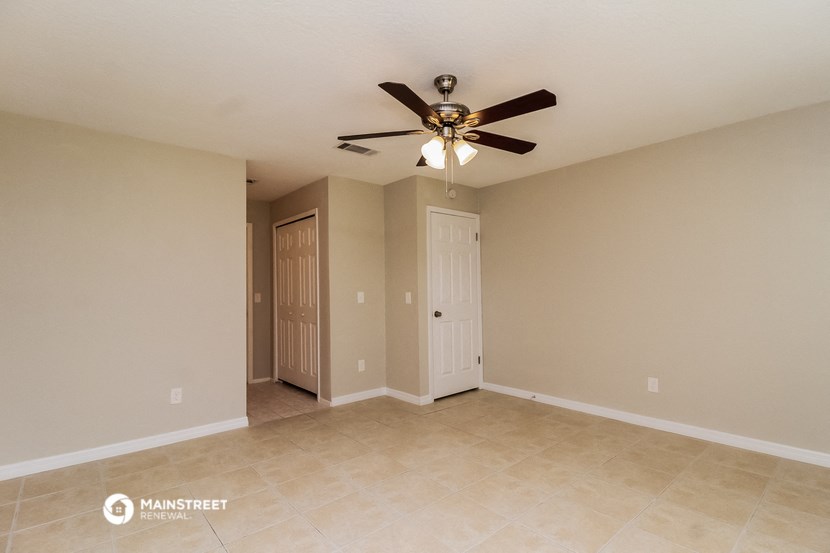 the spacious living room with tile flooring and ceiling fan