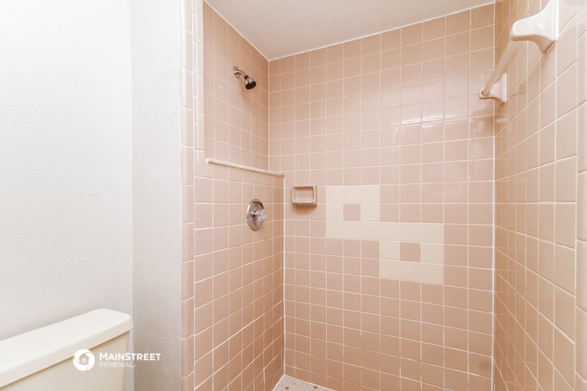 a shower in a bathroom with pink tiles