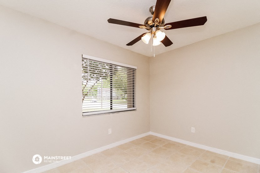 the spacious living room has a ceiling fan and a window