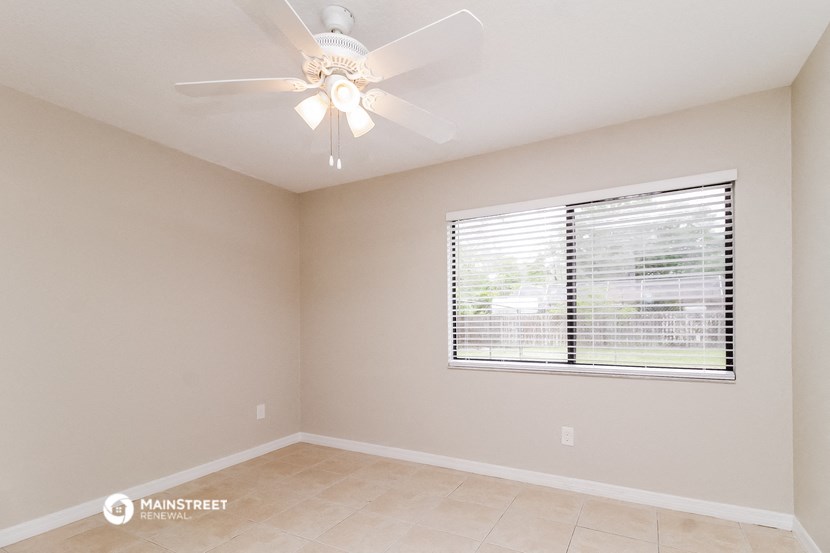 the spacious living room has a ceiling fan and a large window