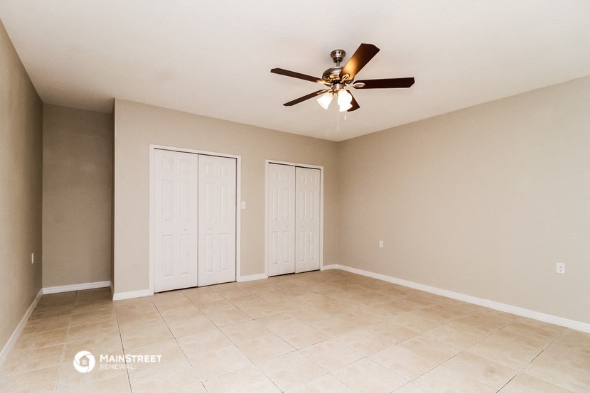 the spacious living room with tile flooring and a ceiling fan