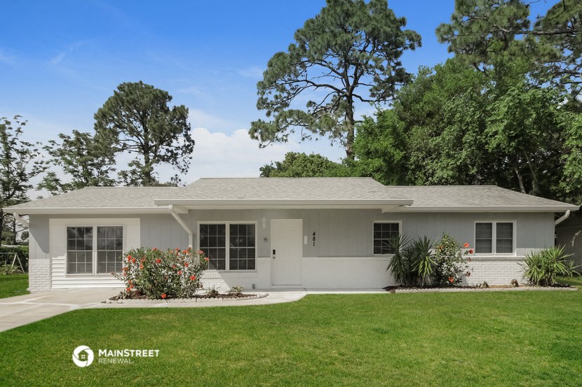 a white house with a lawn and trees