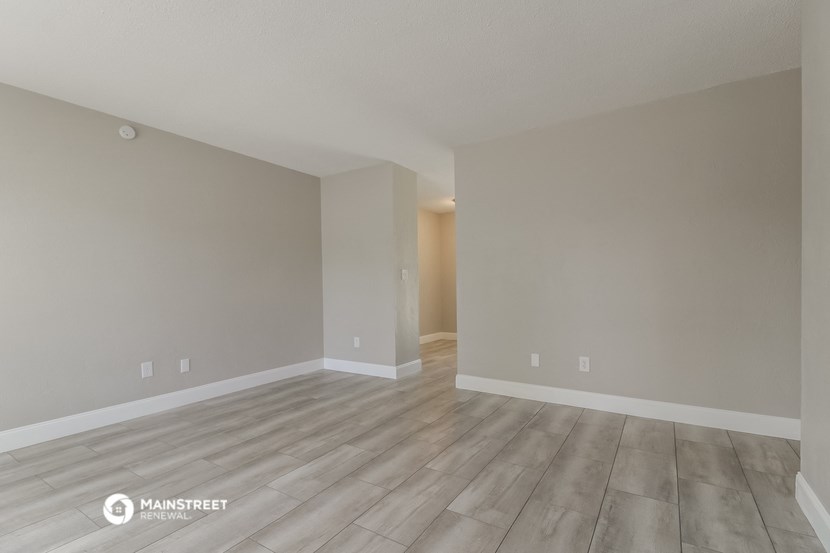 a spacious living room with hardwood floors and grey walls