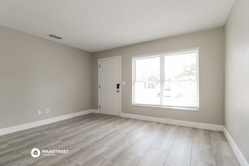 the living room of a new home with a large window and wood flooring