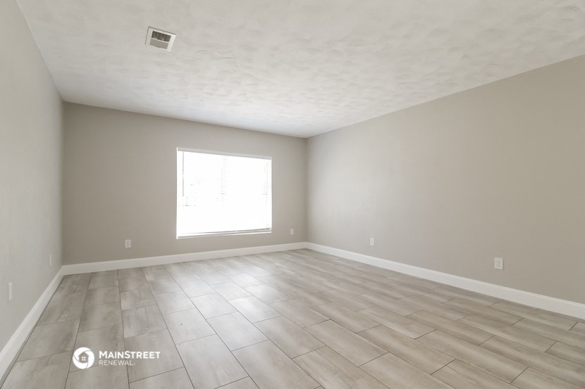 the spacious living room with hardwood floors and a large window