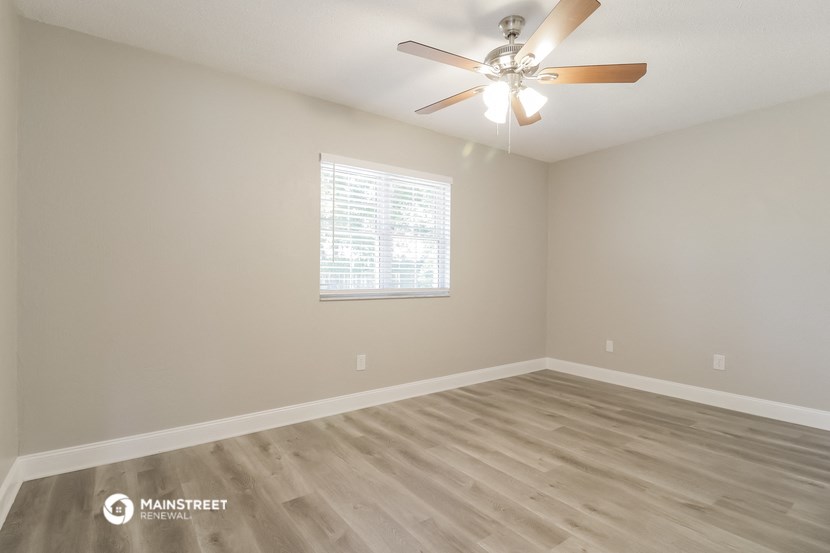the spacious living room with hardwood floors and a ceiling fan