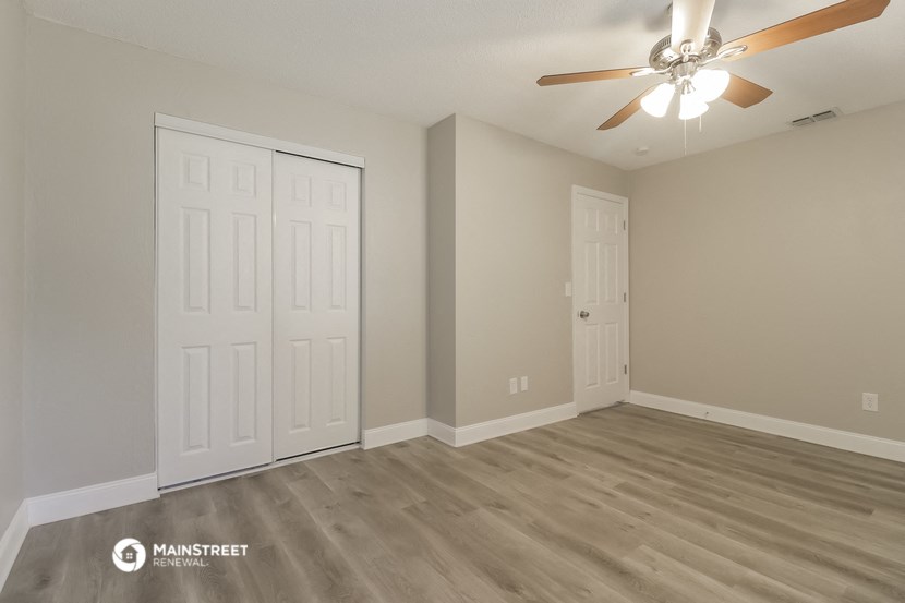 the spacious living room with two closets and a ceiling fan