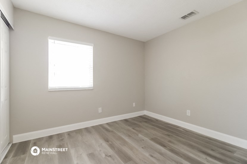 an empty room with wood floors and a window