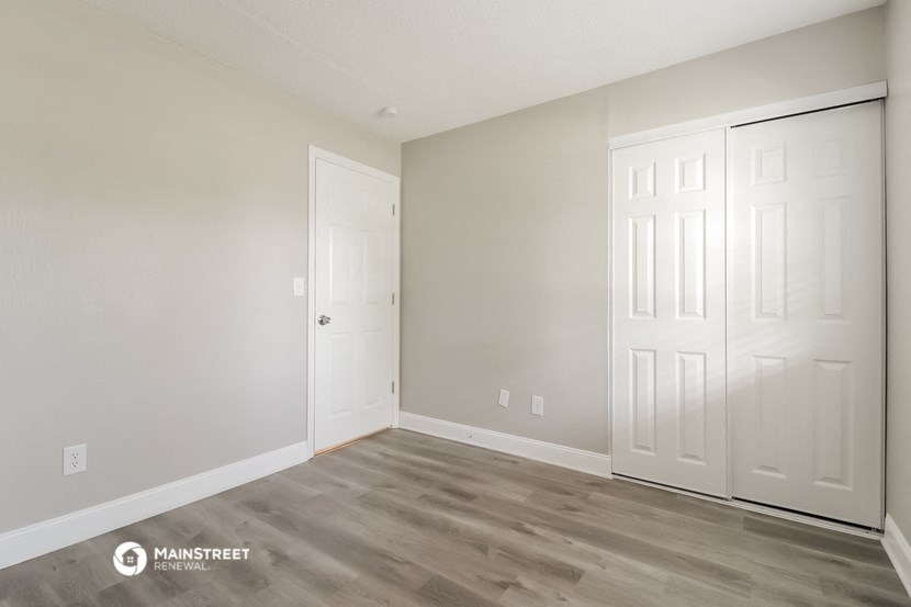 the living room of an apartment with white doors and wood flooring