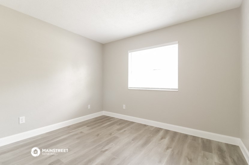an empty room with wooden floors and a window
