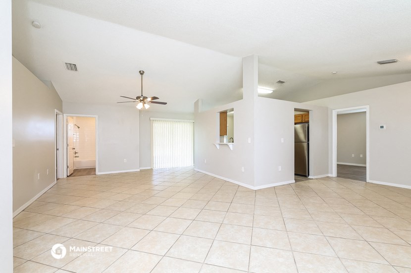 an empty living room with tile flooring and a ceiling fan