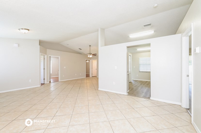 a spacious living room with tile flooring and white walls