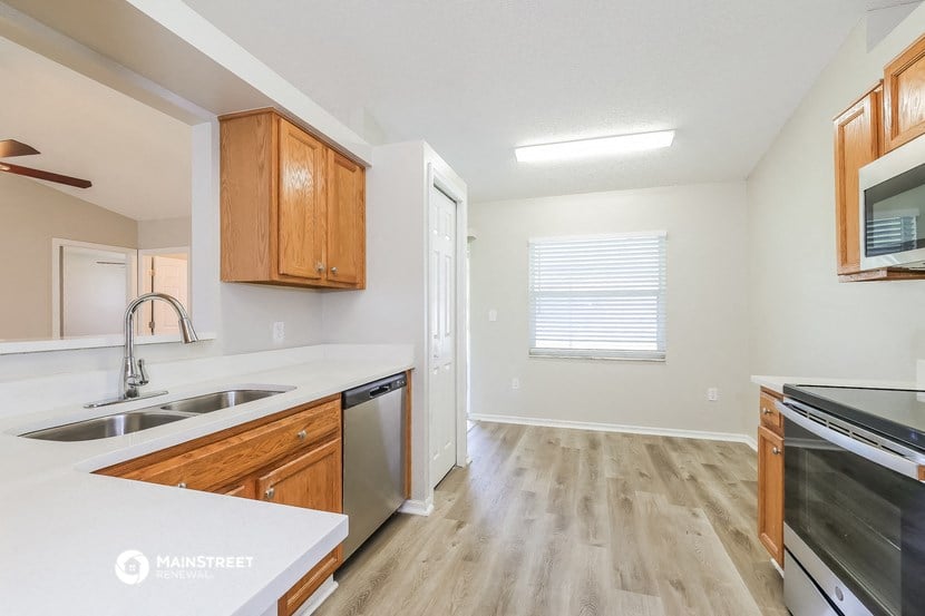 an empty kitchen with wooden cabinets and a white counter top