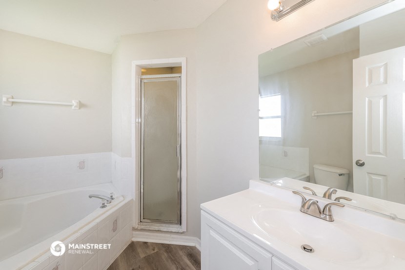 a white bathroom with a tub and a sink and a mirror