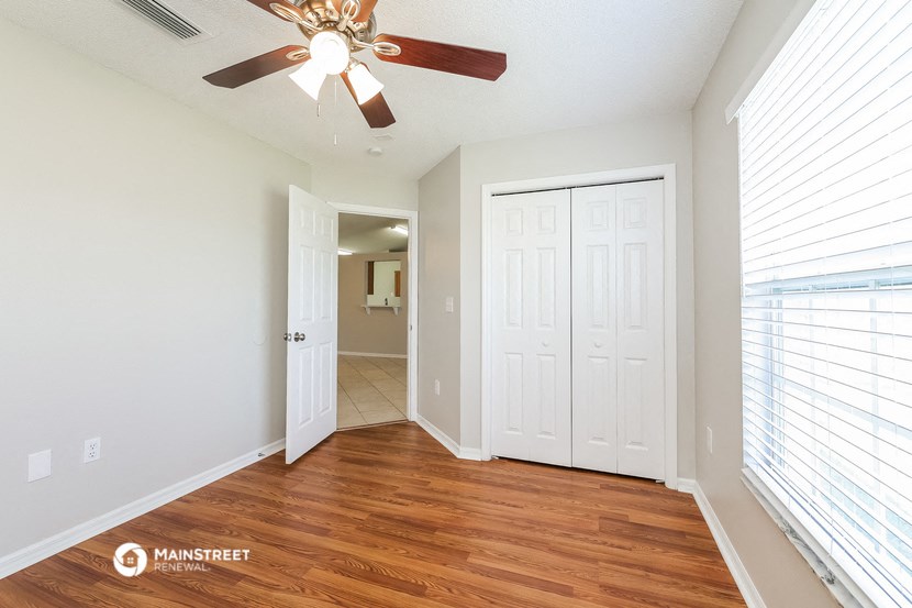 a bedroom with a ceiling fan and a door to a hallway