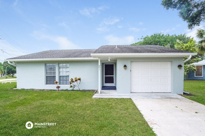 a white house with a white garage door and a lawn