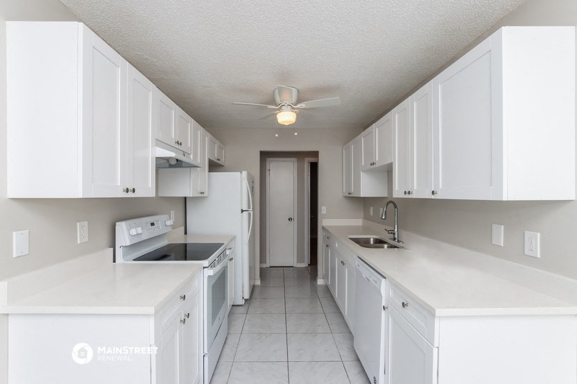 an empty kitchen with white cabinets and a ceiling fan