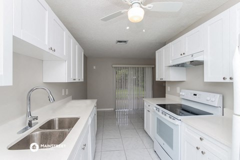 a kitchen with white cabinets and a sink and a stove