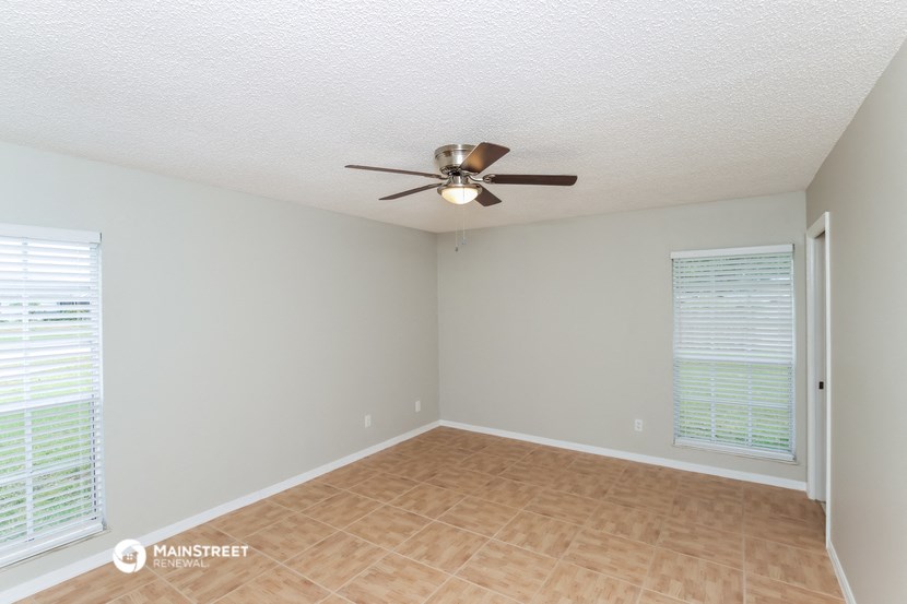 an empty living room with a ceiling fan and a window