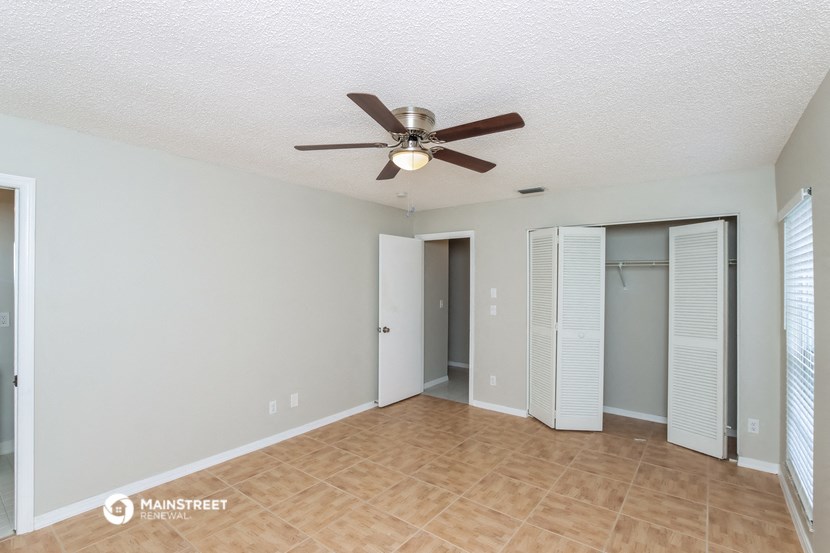 an empty living room with a ceiling fan and a closet