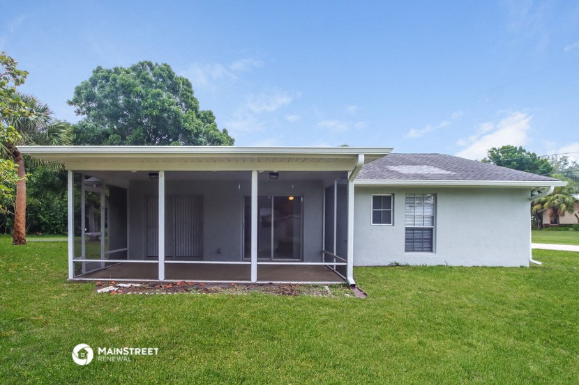 a small white house with a porch and a lawn