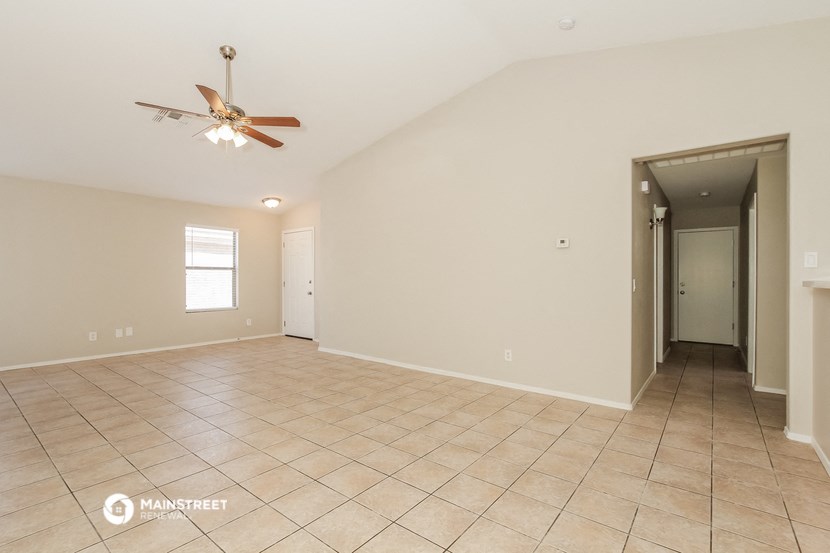 the spacious living room with tile flooring and a ceiling fan