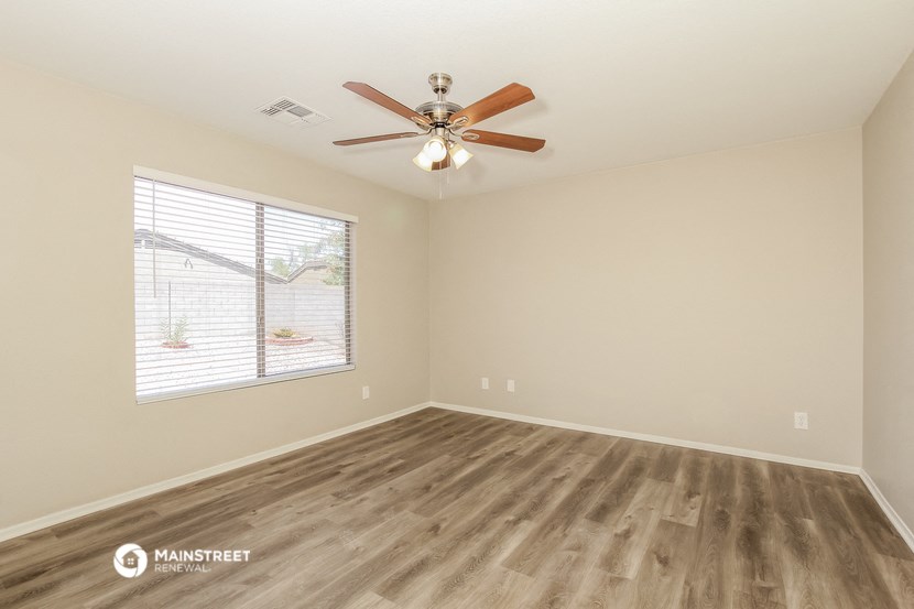 the spacious living room with wood flooring and a ceiling fan