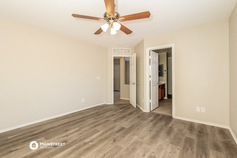 the spacious living room with wood flooring and a ceiling fan