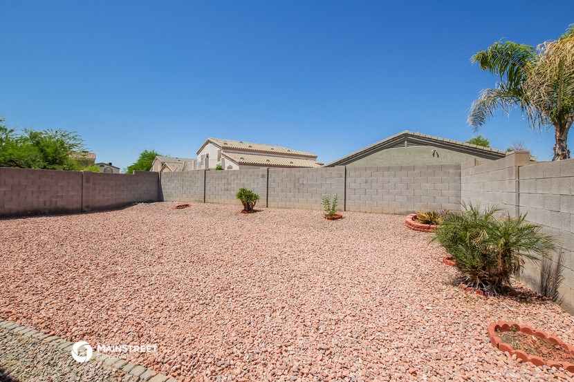 a backyard with a retaining wall and palm trees