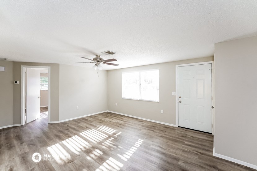 an empty living room with a ceiling fan
