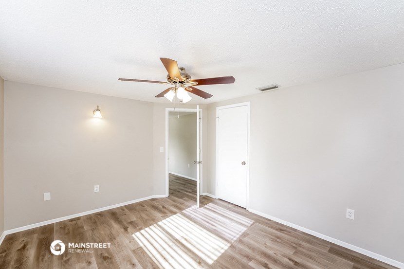 the spacious living room with ceiling fan and wood flooring