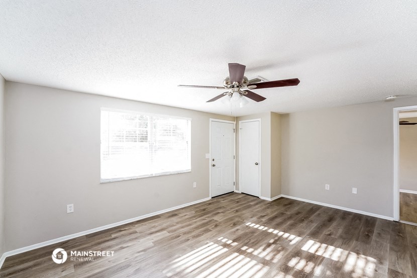 an empty living room with a ceiling fan and a window