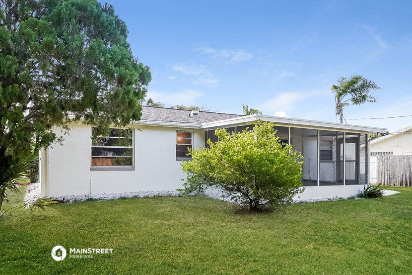 a small white house with a lawn and a tree