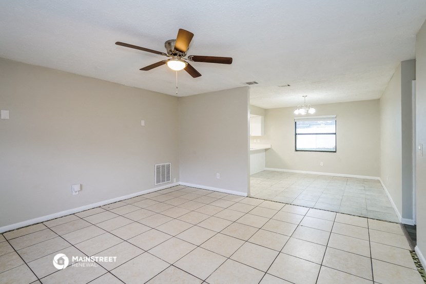 the living room and dining room of an empty house with a ceiling fan