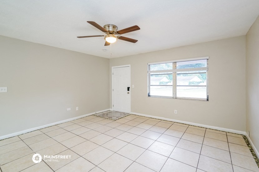 an empty living room with a ceiling fan and a window