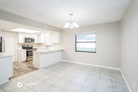 an open kitchen and living room with white cabinets and tile flooring
