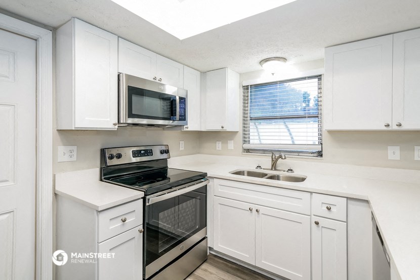 a white kitchen with white cabinets and a black stove and a microwave