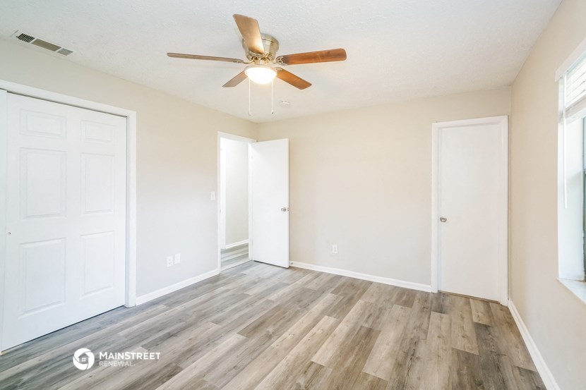 an empty living room with wood flooring and a ceiling fan
