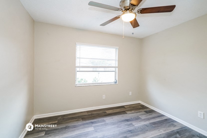 an empty room with a ceiling fan and a window